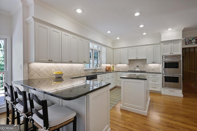 2000 Old Dominion Rd, Atlanta, GA 30350 - kitchen featuring light wood-type flooring, crown molding, a breakfast bar area, and stainless steel appliances