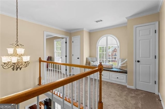 hall with visible vents, baseboards, a notable chandelier, ornamental molding, and carpet flooring