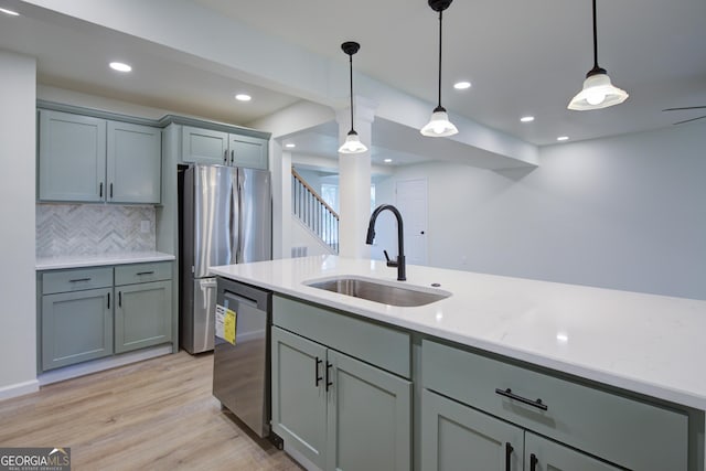 kitchen with a sink, gray cabinets, light wood-style flooring, and stainless steel appliances