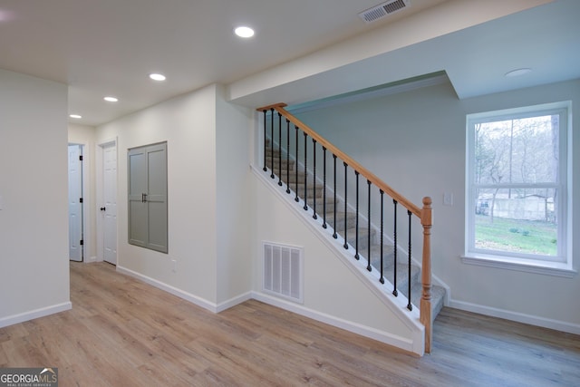stairs with wood finished floors, baseboards, visible vents, and recessed lighting