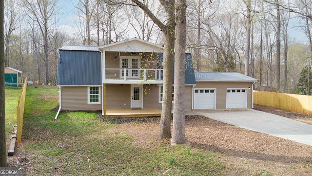 view of front of home with metal roof, a balcony, a front lawn, and driveway