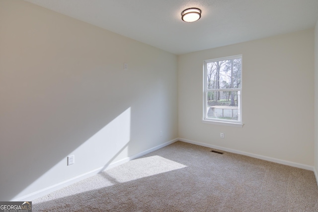 carpeted spare room with baseboards and visible vents
