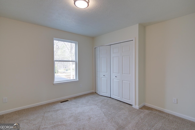 unfurnished bedroom featuring a textured ceiling, baseboards, visible vents, and carpet floors