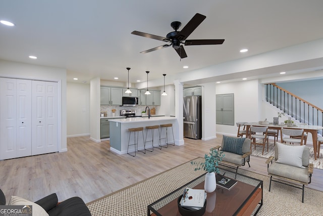 living area featuring ceiling fan, recessed lighting, stairway, light wood finished floors, and baseboards