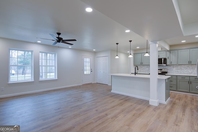 kitchen featuring tasteful backsplash, light wood-type flooring, gray cabinets, light countertops, and stainless steel appliances
