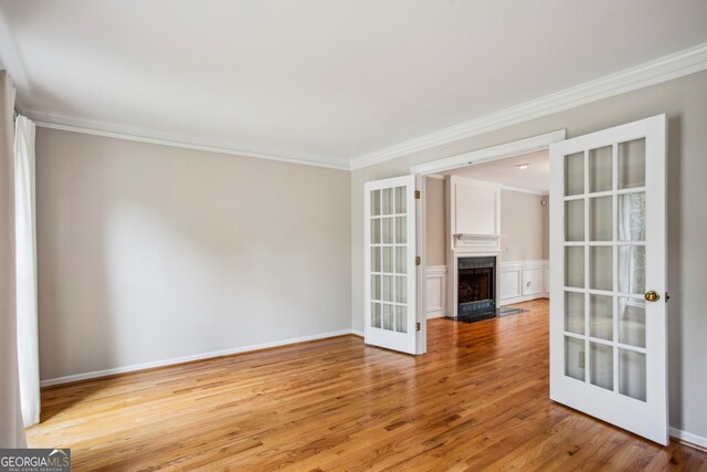 4284 Windy Gap Ct NW, Kennesaw, GA 30144 - spare room featuring baseboards, ornamental molding, french doors, a fireplace with flush hearth, and light wood-style floors
