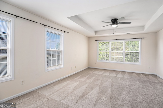 carpeted spare room with baseboards, ceiling fan, and a tray ceiling