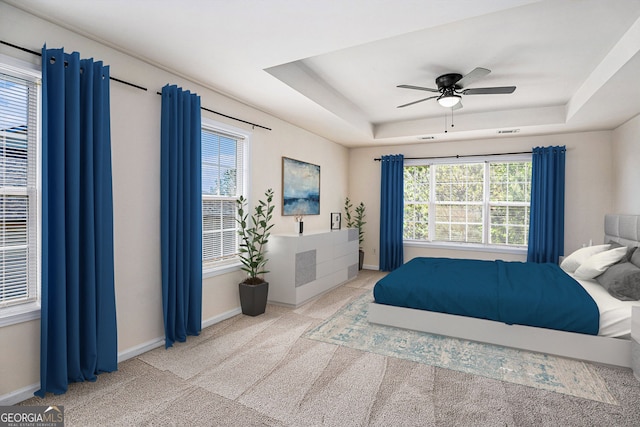 bedroom featuring a raised ceiling, carpet floors, a ceiling fan, baseboards, and visible vents