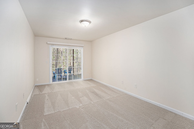 empty room featuring baseboards, visible vents, and light carpet