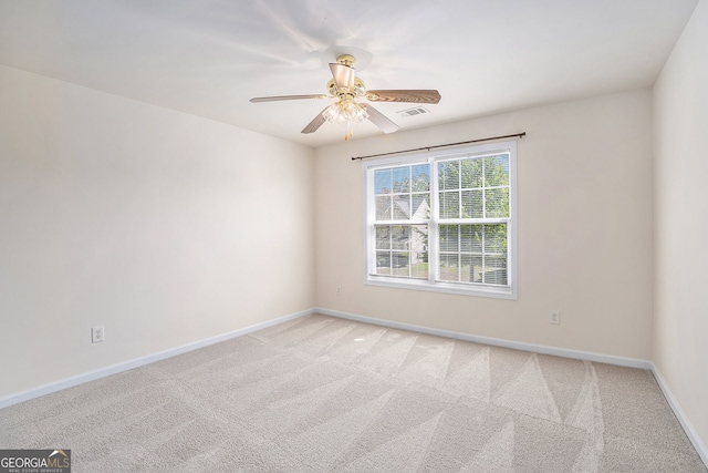 spare room featuring baseboards, ceiling fan, light carpet, and visible vents