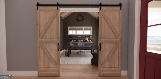 entrance foyer featuring a barn door, light wood-style floors, and baseboards