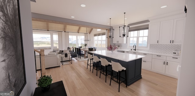 kitchen featuring white cabinets, a kitchen breakfast bar, light wood finished floors, and tasteful backsplash