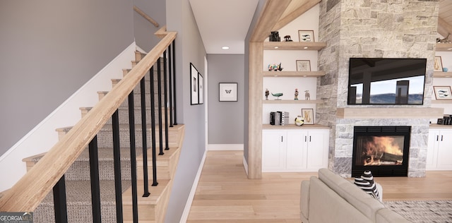 bar featuring stairway, light wood-type flooring, a fireplace, baseboards, and recessed lighting