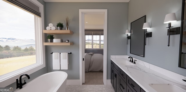 ensuite bathroom with tile patterned flooring, double vanity, a sink, and a freestanding bath