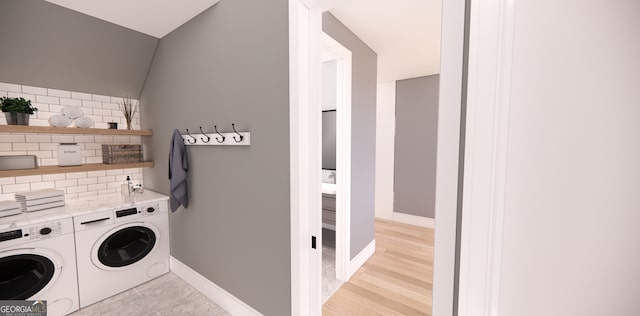 washroom featuring baseboards, laundry area, light wood-type flooring, and washer and clothes dryer