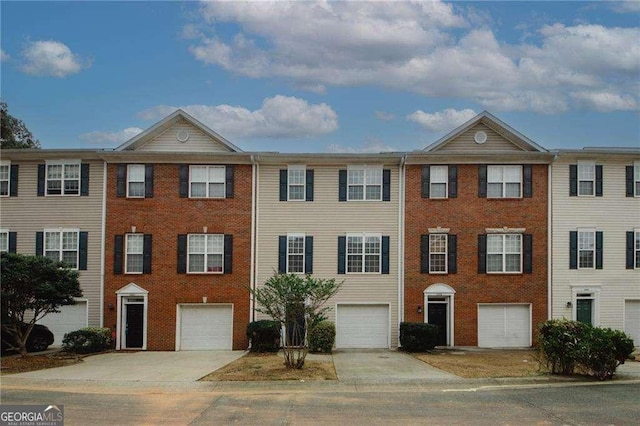 townhome / multi-family property with brick siding, driveway, and an attached garage