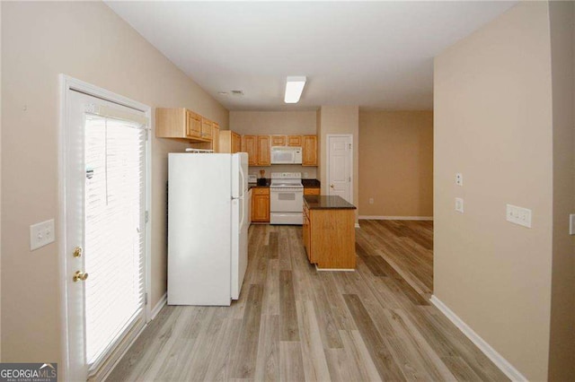 kitchen with a center island, baseboards, dark countertops, white appliances, and light wood-style flooring