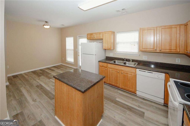 kitchen with a sink, a center island, light wood-type flooring, and white appliances