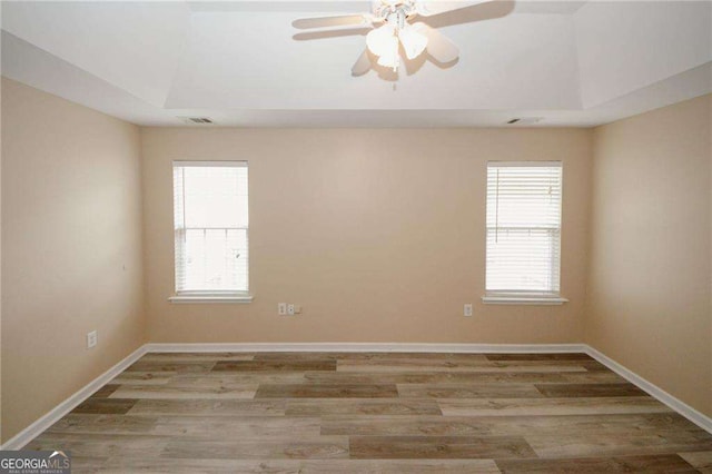 spare room featuring visible vents, baseboards, a ceiling fan, and wood finished floors