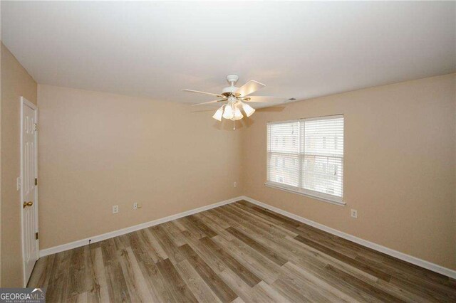 empty room with wood finished floors, baseboards, and a ceiling fan