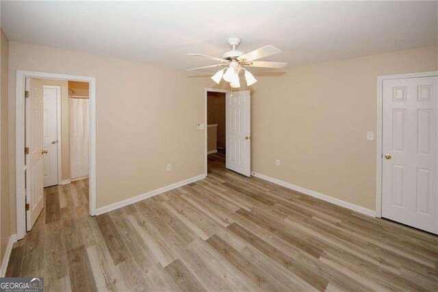 interior space featuring ceiling fan, light wood-style floors, and baseboards