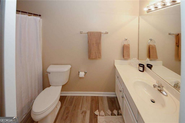 full bath featuring toilet, wood finished floors, vanity, and baseboards