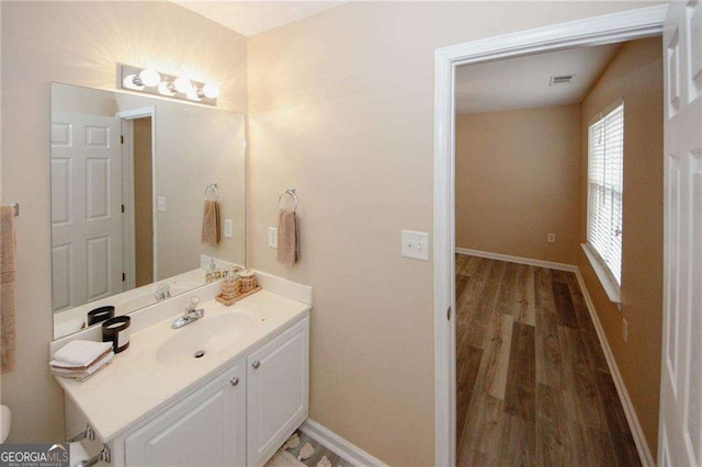 bathroom with vanity, baseboards, toilet, visible vents, and wood finished floors