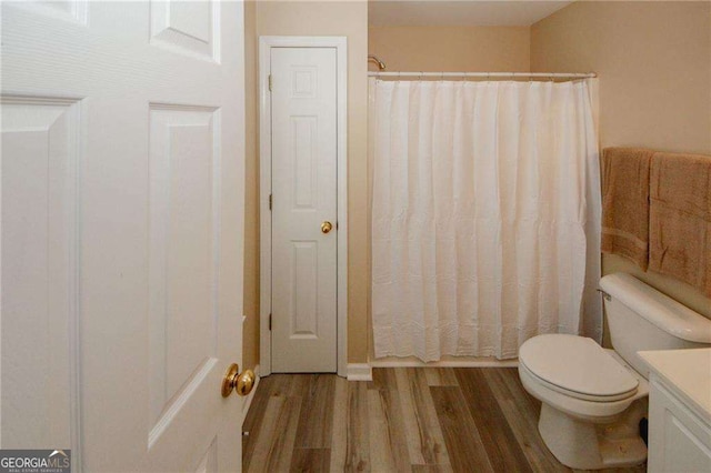 full bathroom with curtained shower, vanity, toilet, and wood finished floors