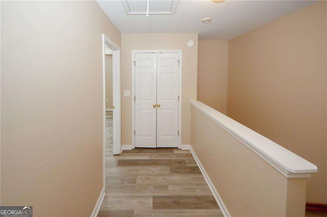 hall featuring light wood-style flooring and baseboards
