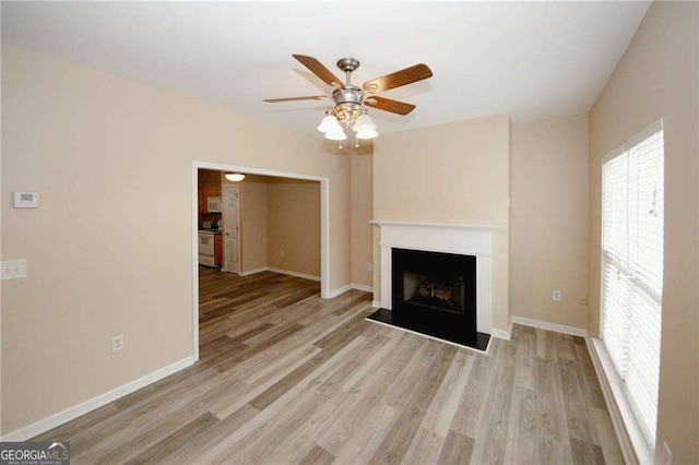 unfurnished living room with baseboards, a ceiling fan, and wood finished floors
