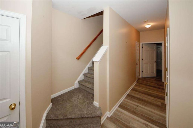 staircase featuring baseboards and wood finished floors