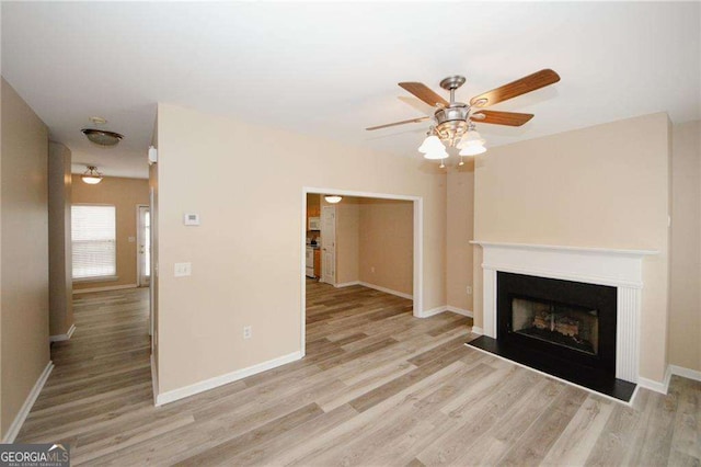 unfurnished living room with light wood-style flooring, a ceiling fan, and baseboards