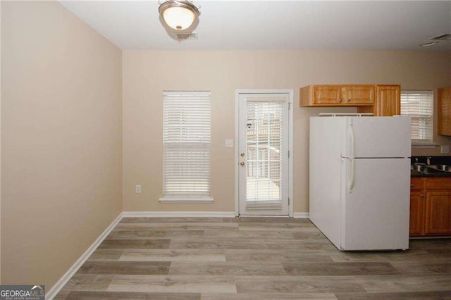 kitchen featuring light wood-style flooring, freestanding refrigerator, and baseboards