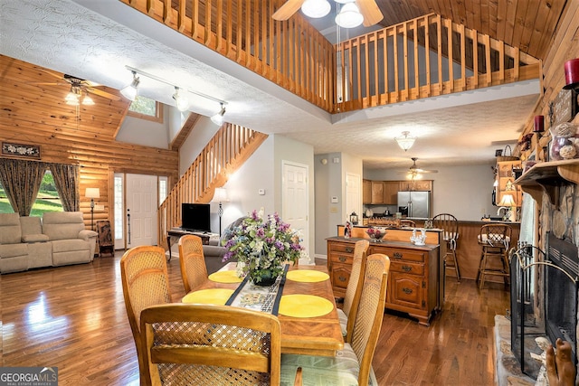 dining area featuring ceiling fan, high vaulted ceiling, and rustic walls