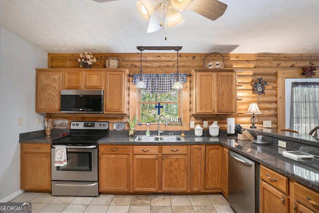 kitchen featuring a sink, log walls, pendant lighting, ceiling fan, and appliances with stainless steel finishes