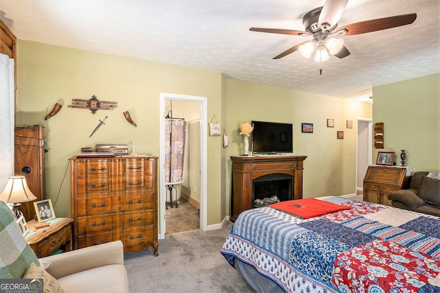 bedroom with carpet, a fireplace, a textured ceiling, baseboards, and ceiling fan
