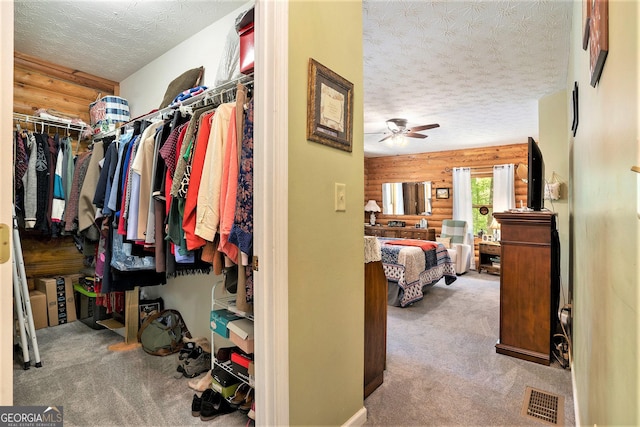walk in closet with carpet, visible vents, and ceiling fan