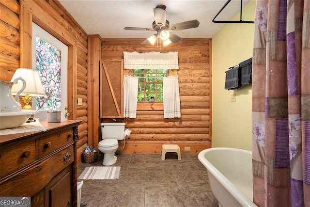 bathroom with vanity, toilet, rustic walls, and a freestanding tub