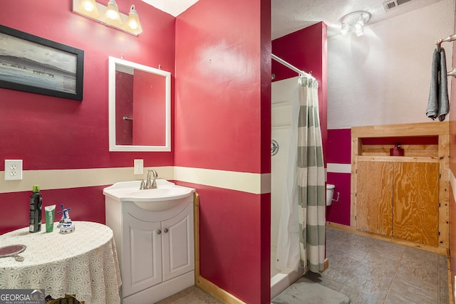 bathroom with a stall shower, vanity, and baseboards