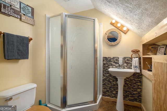bathroom featuring toilet, lofted ceiling, a textured ceiling, and a shower stall