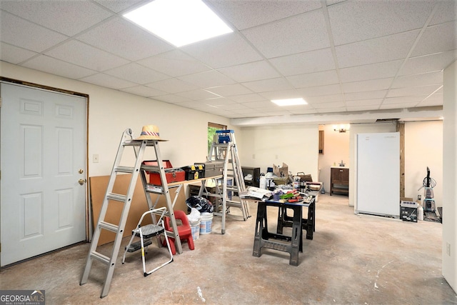 below grade area featuring a paneled ceiling and freestanding refrigerator