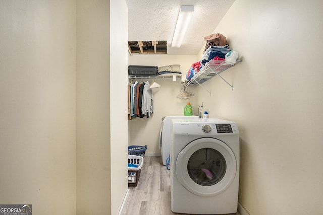 washroom with separate washer and dryer, laundry area, light wood-type flooring, and baseboards
