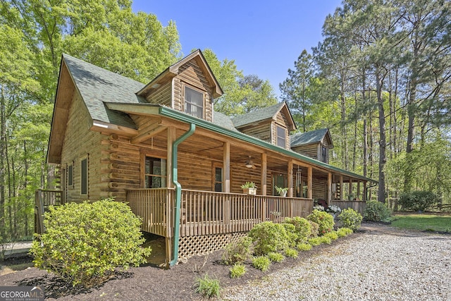 view of side of home featuring covered porch, a shingled roof, a ceiling fan, and log exterior