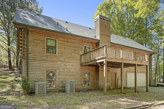 rear view of house featuring central air condition unit, a shingled roof, a garage, and a deck