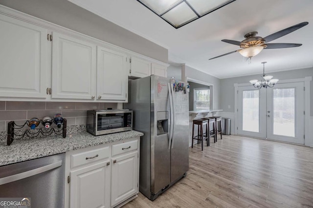 182 Hickory Dr, Ringgold, GA 30736 - kitchen with light wood-type flooring, appliances with stainless steel finishes, white cabinetry, ceiling fan with notable chandelier, and backsplash