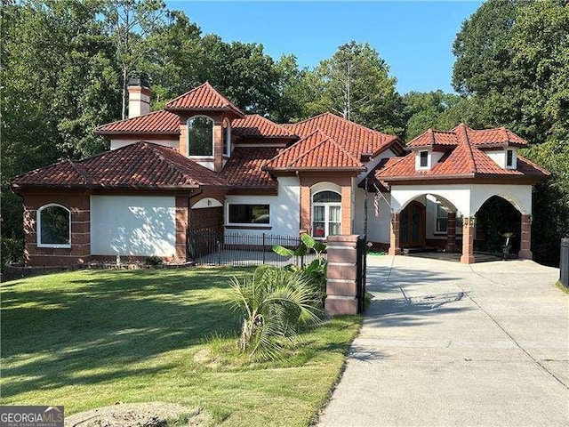 mediterranean / spanish-style home with a front yard, a tiled roof, a chimney, and a fenced front yard
