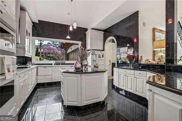 kitchen with white cabinets, dark countertops, granite finish floor, and decorative light fixtures
