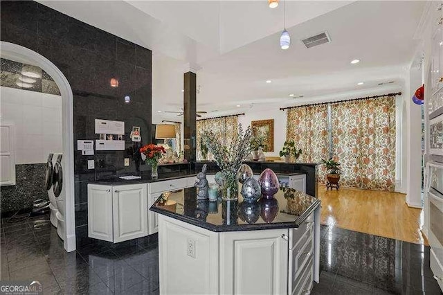 kitchen with white cabinets, recessed lighting, visible vents, a kitchen island, and dark countertops