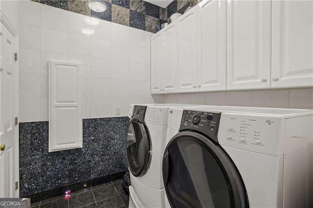 washroom with independent washer and dryer, tile patterned floors, and tile walls