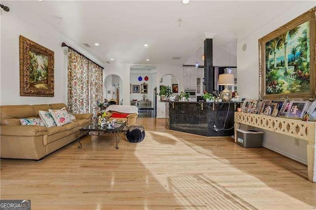 living area featuring recessed lighting, arched walkways, and wood finished floors